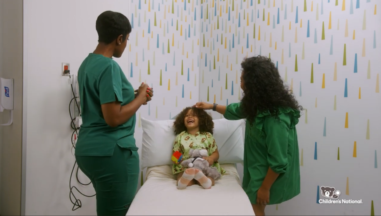 Nurses taking care of a smiling child in a hospital bed