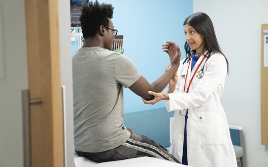 Anisha Abraham, MD, chief of Adolescent and Young Adult Medicine at Children's National Hospital, examines the arm of a teen patient.