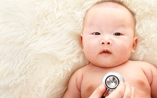 A baby with a healthcare provider listening to their heart via a stethoscope