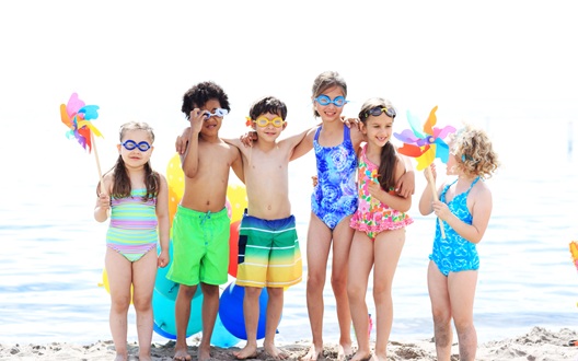 A group of young kids in bathing suits at the beach