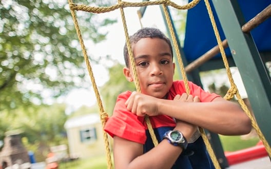 A boy in a red t-shirt playing on the playground