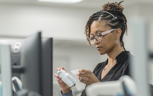 A woman working in the Children's National Specialty Pharmacy puts a label on a prescription bottle