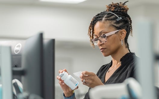 A woman working in the Children's National Specialty Pharmacy puts a label on a prescription bottle