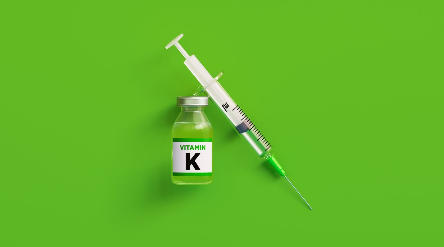 Vitamin K shot on green background