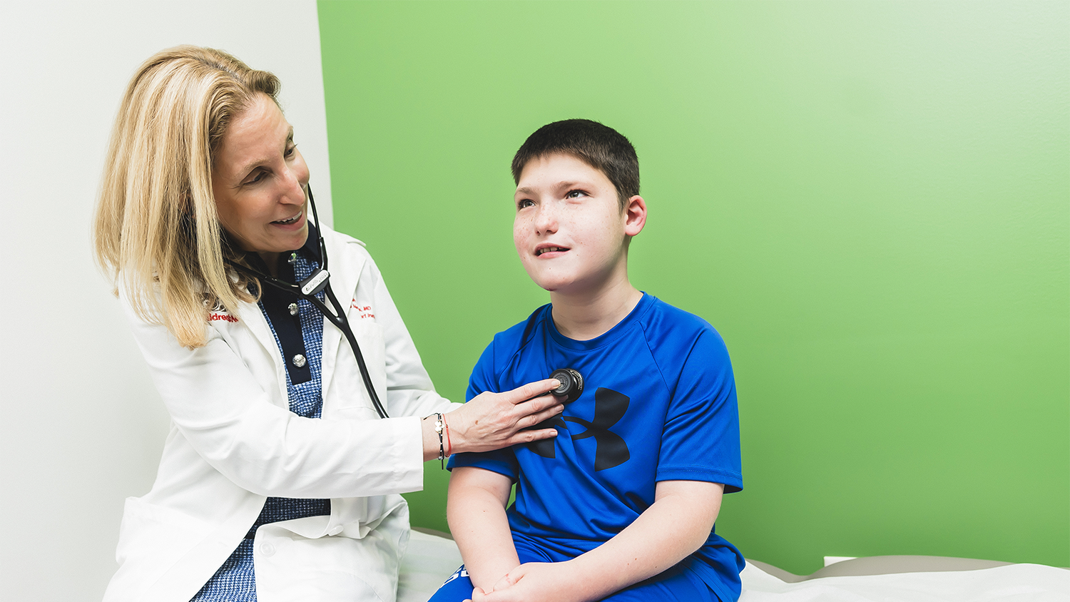 Doctor checking a young boys heart with a stethoscope.