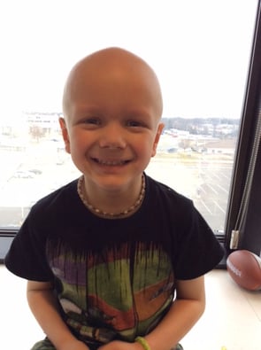 Brayden with a bald head smiling at the camera