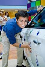 Marco smiling while decorating a white car with blue handprints