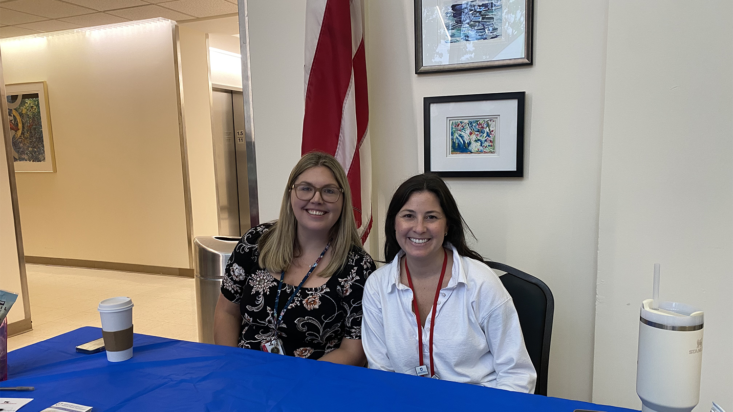 Two women sitting at a convention/information table.