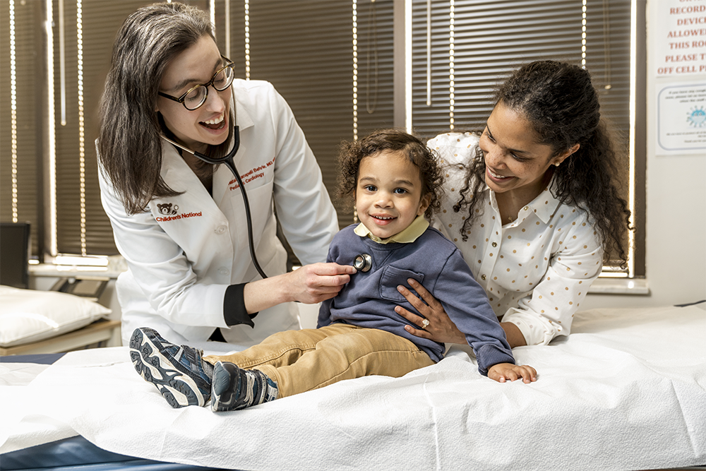 Doctor and mother holding toddler on an exam bed for a check up