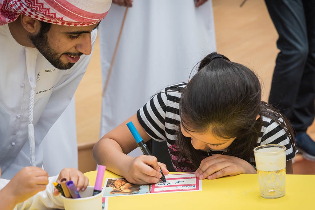 girl coloring with man at table 