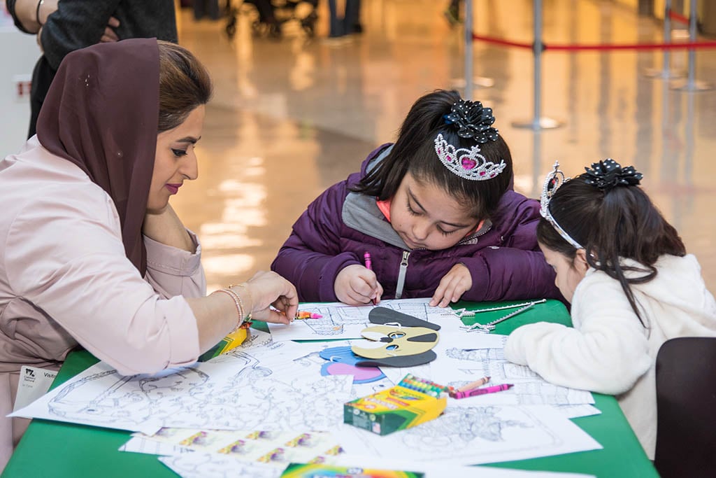 girl coloring with woman at table 