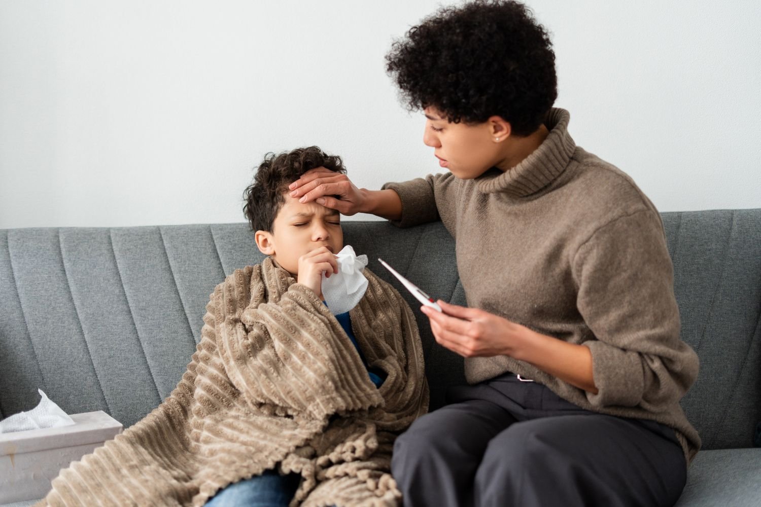mother checking temperature of sick son