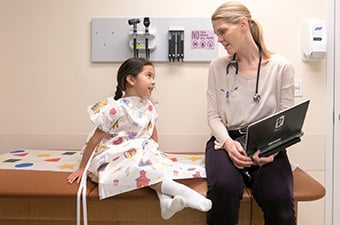 Young girl seated on table talking to doctor