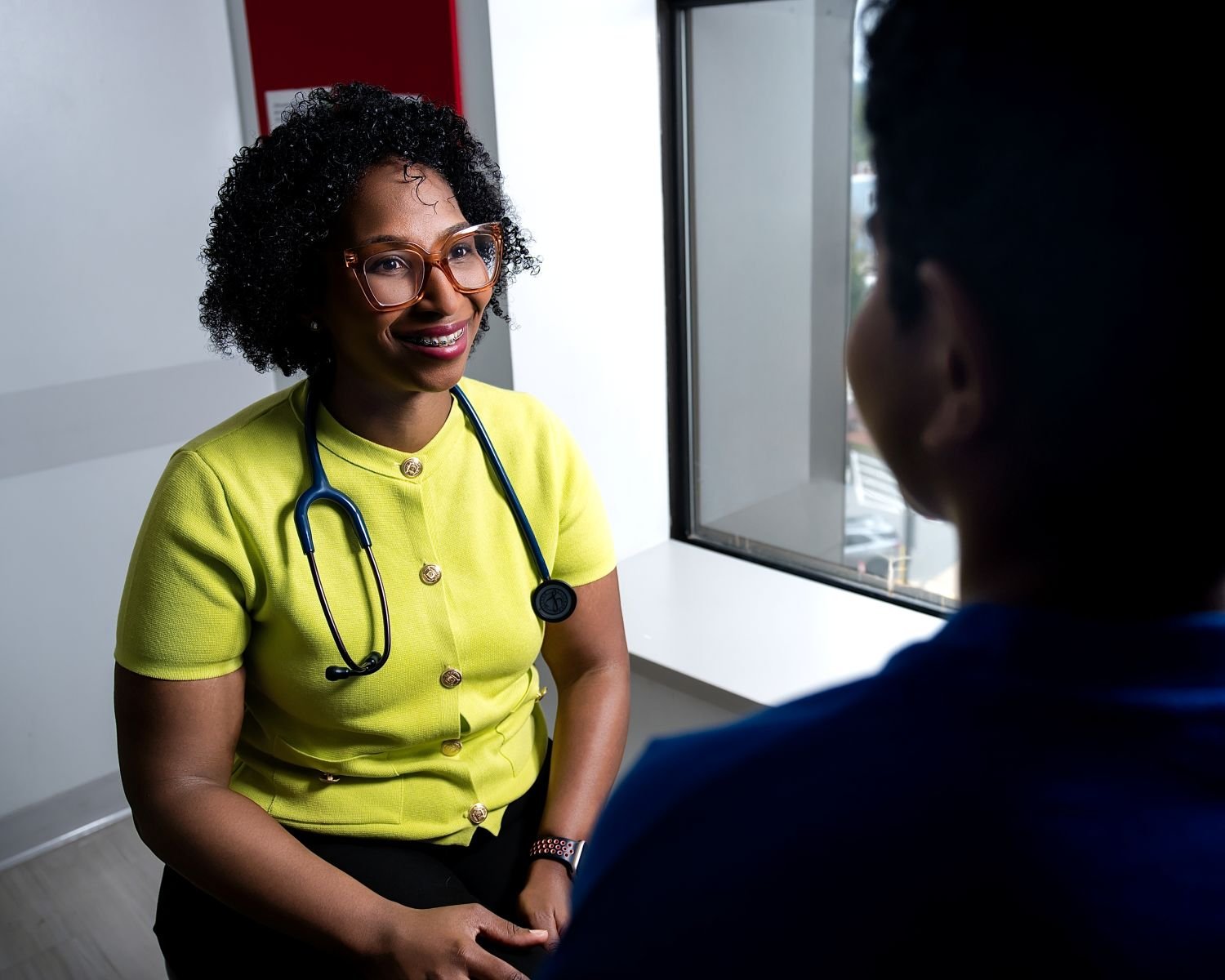 Provider in yellow shirt smiling at a patient