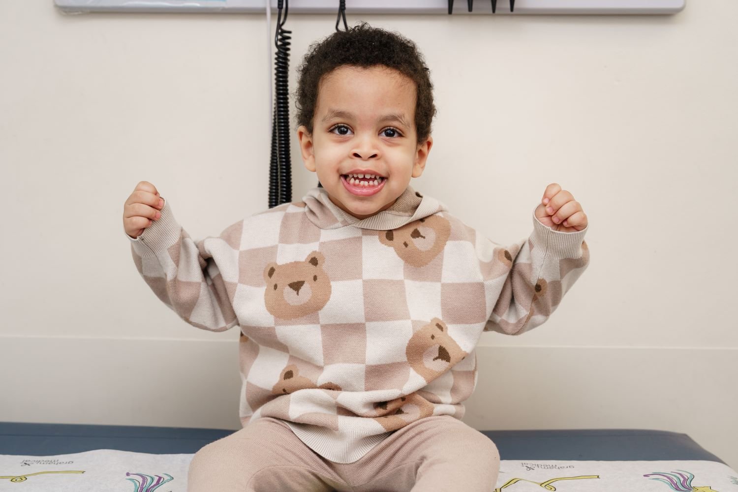 young boy smiling on exam table