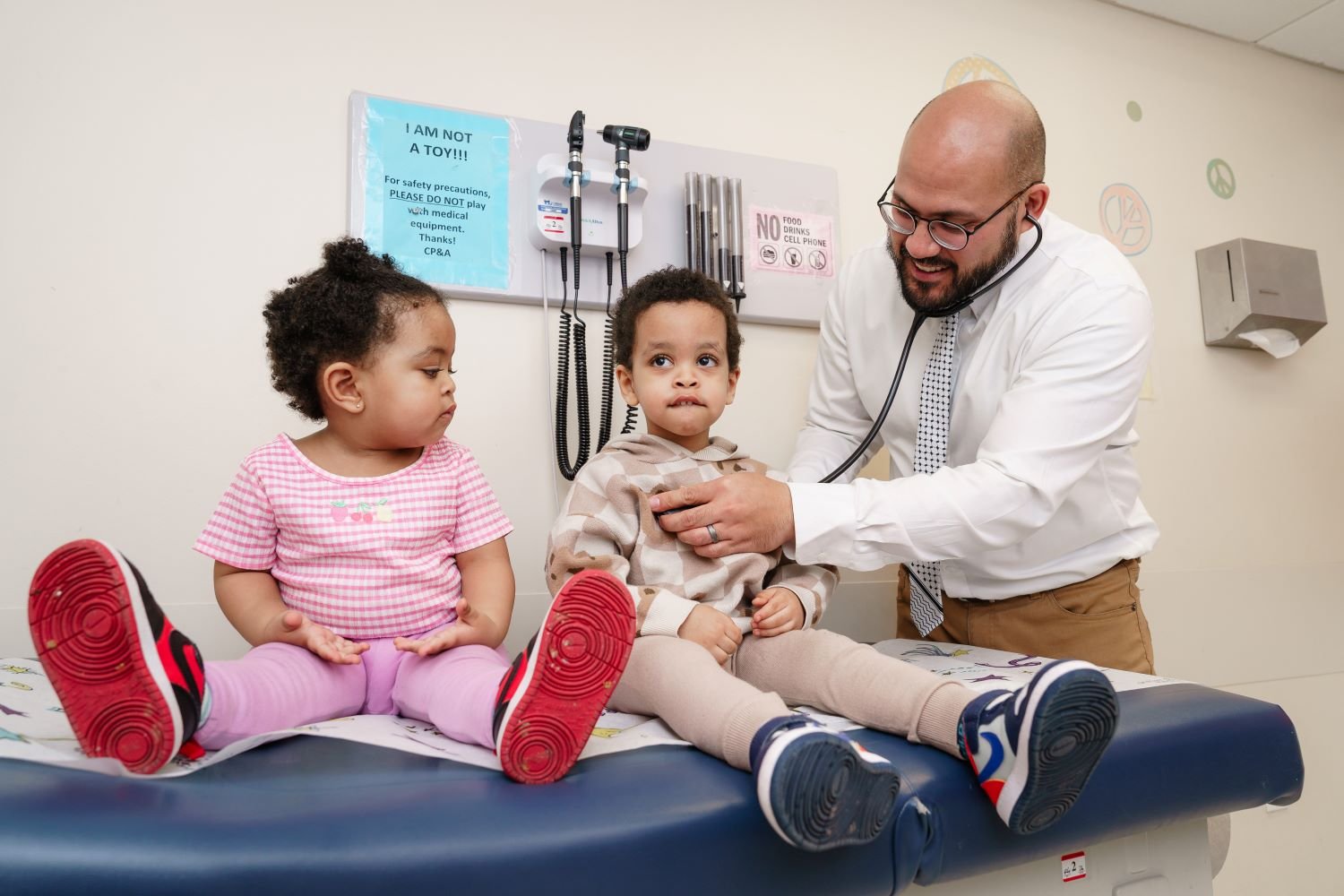 Doctor examines brother and sister on an exam table