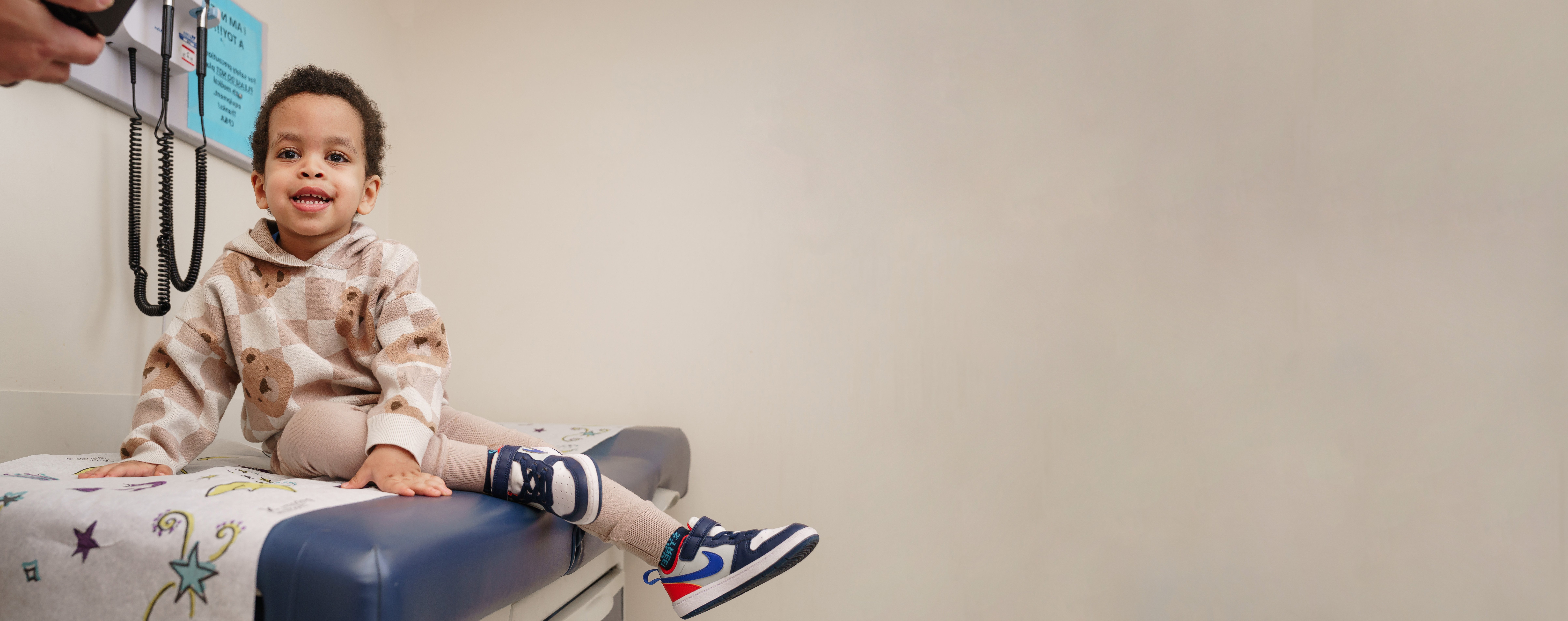 young boy smiling on exam table