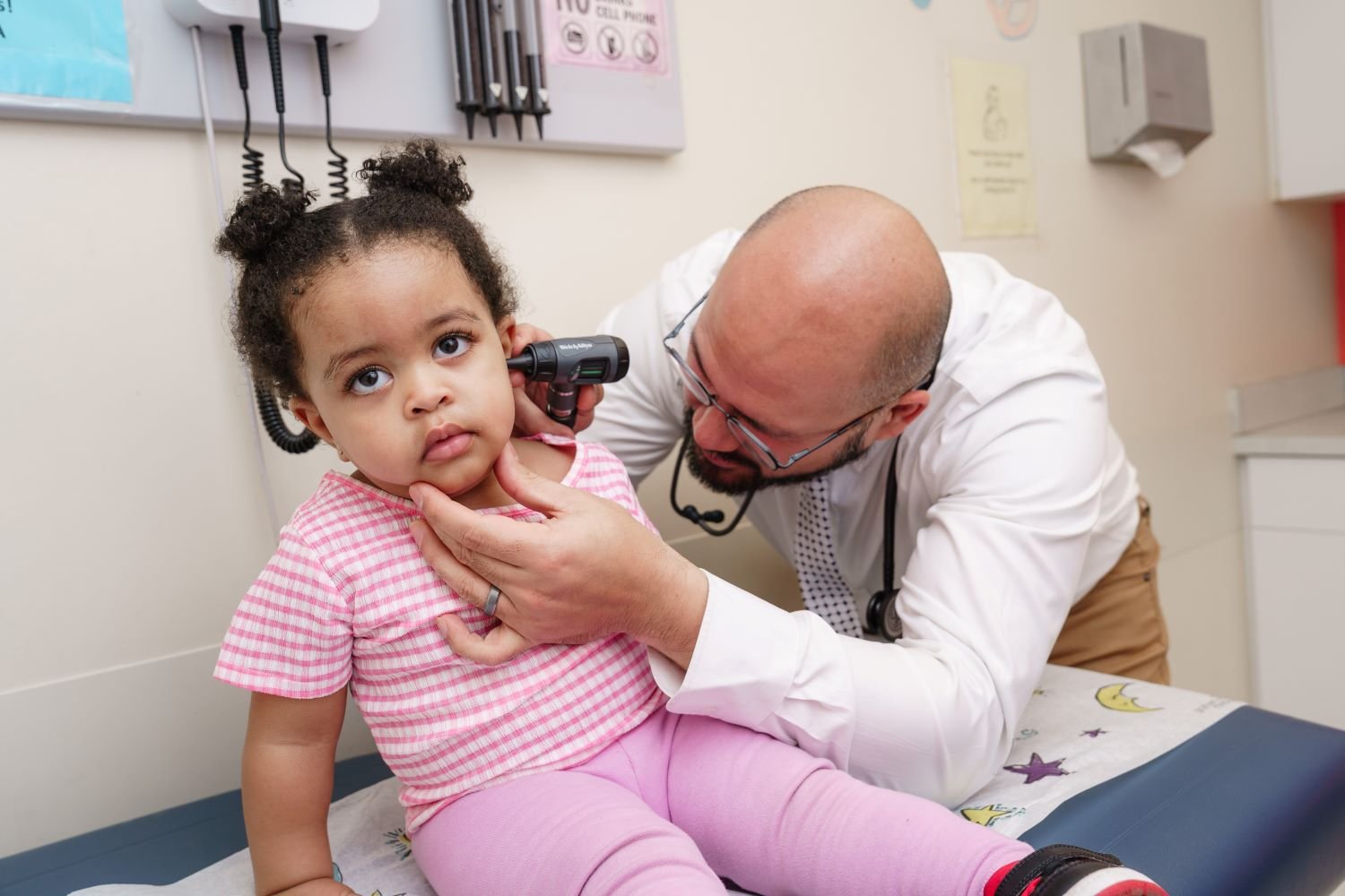 Doctor looks inside young patient's ear