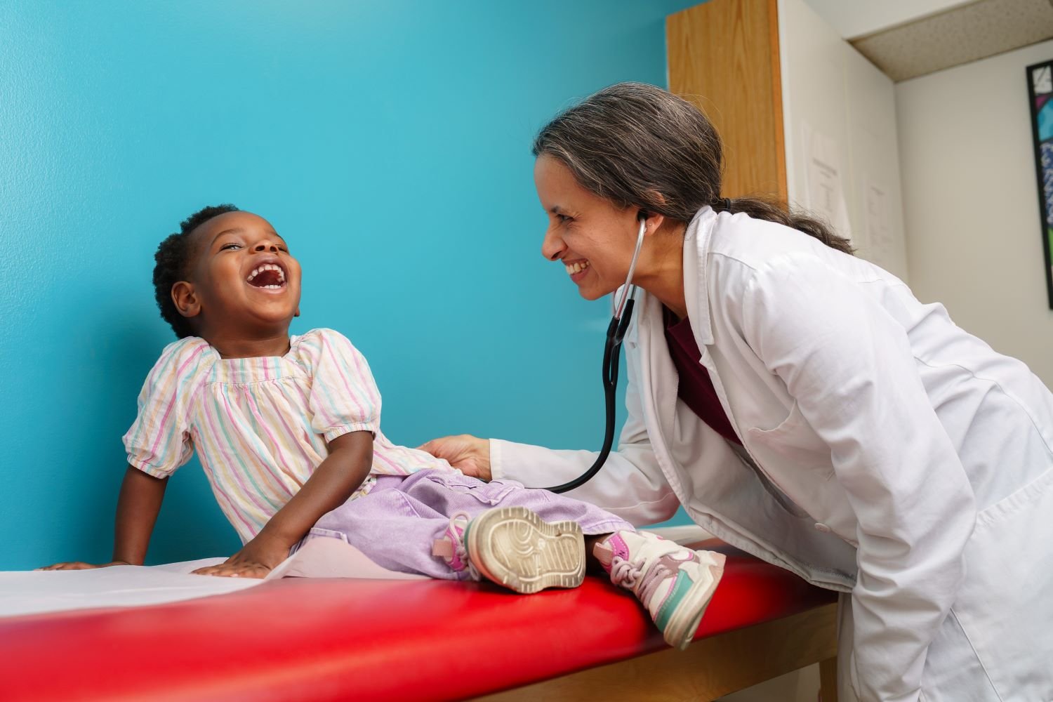 doctor laughs with young patient during an appointment