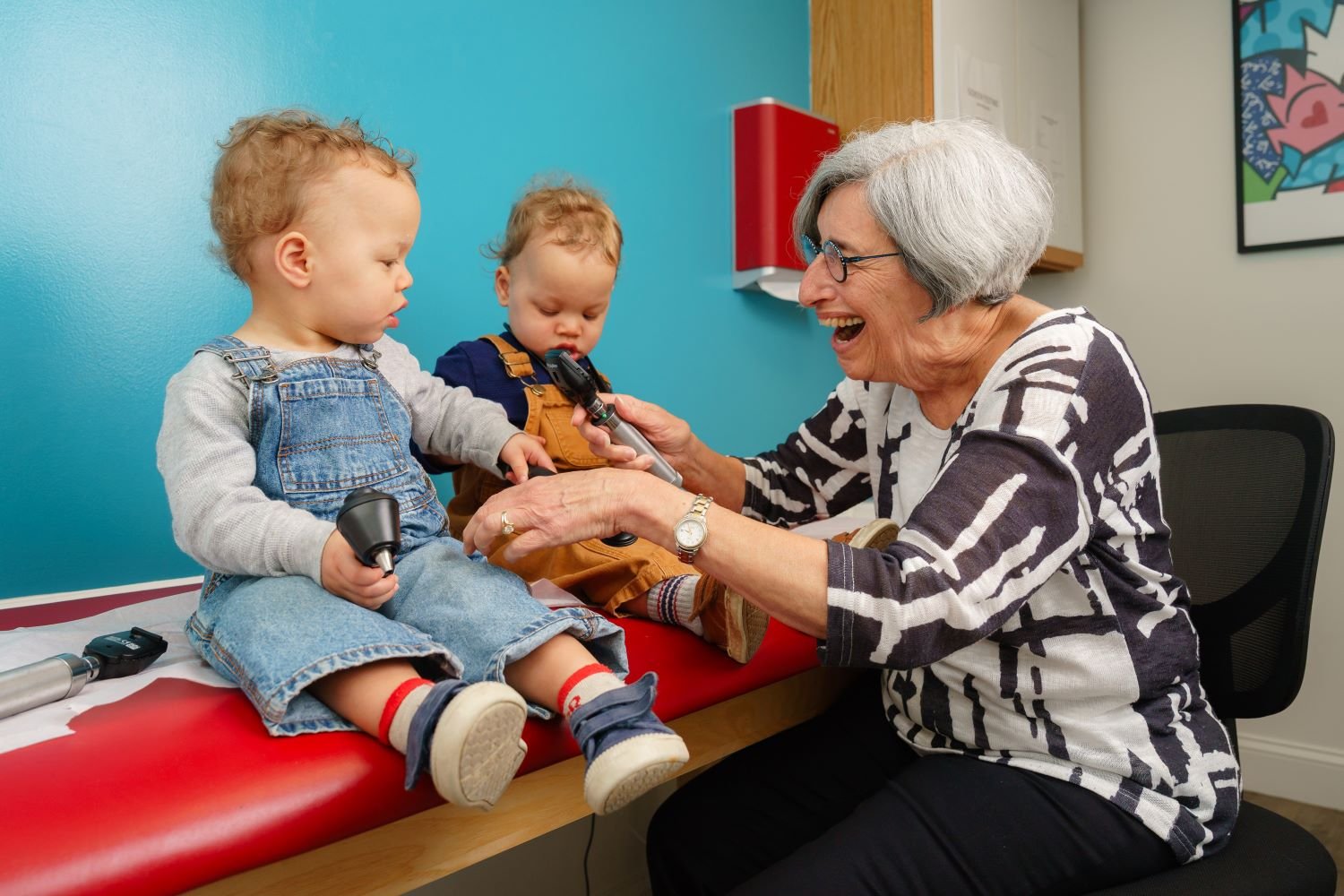 smiling doctor interacts with two babies