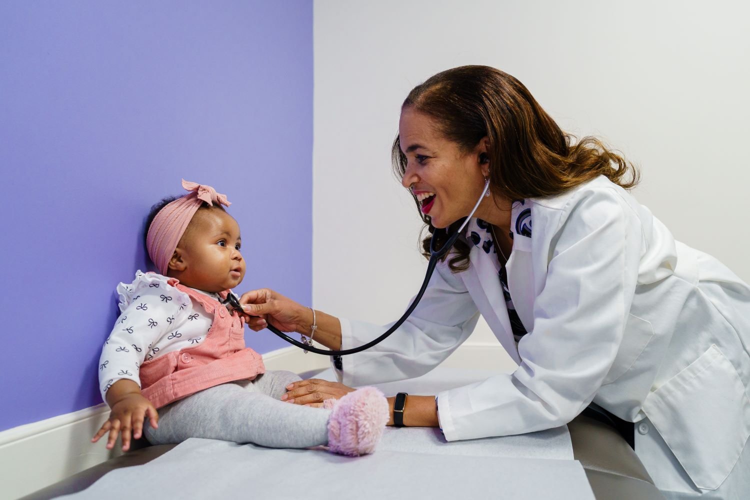 Smiling doctor listens to baby's heart
