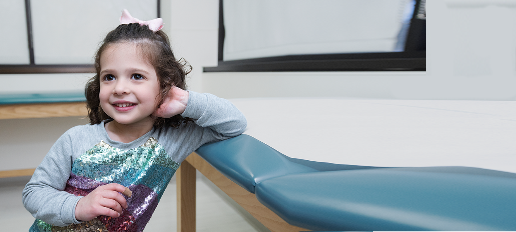 young girl smiling next to exam table