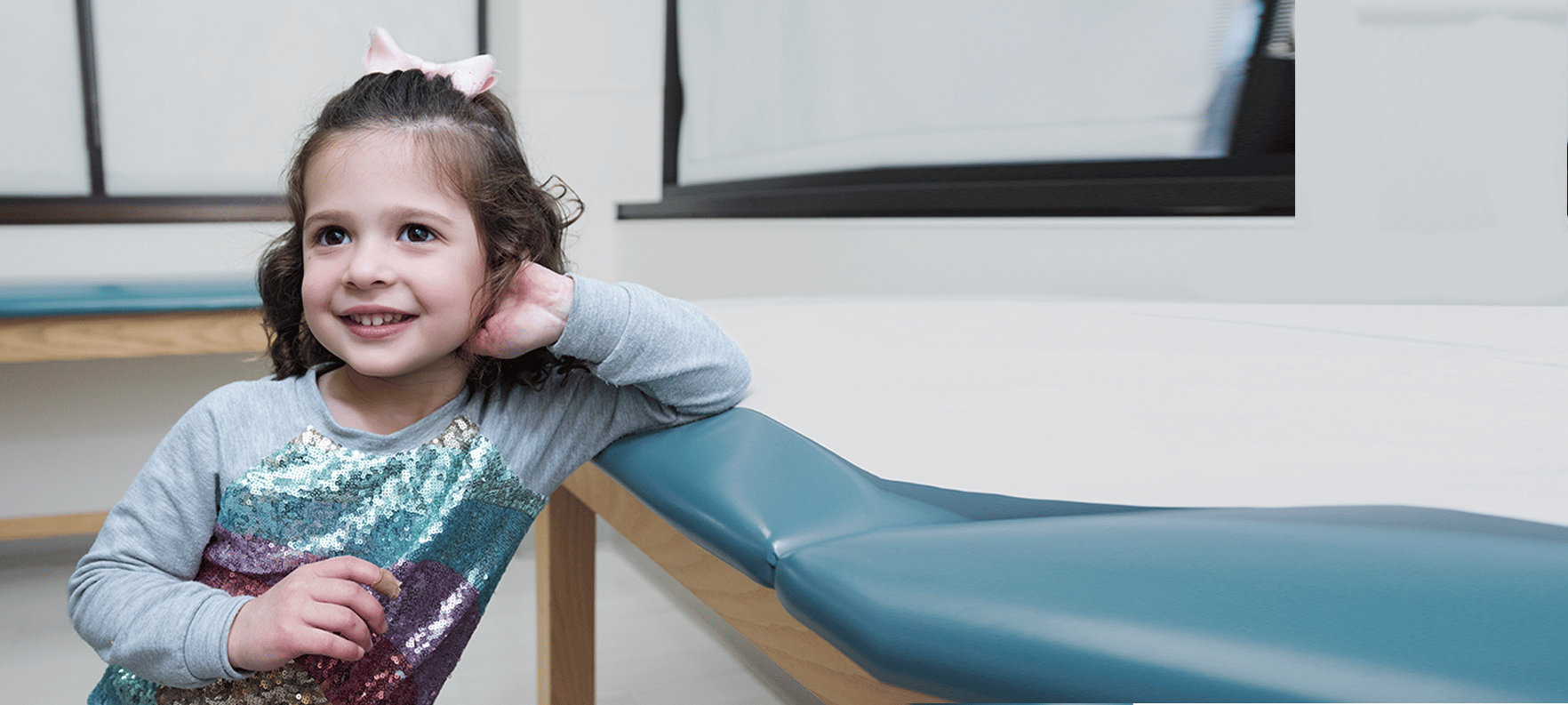 young girl smiling next to exam table