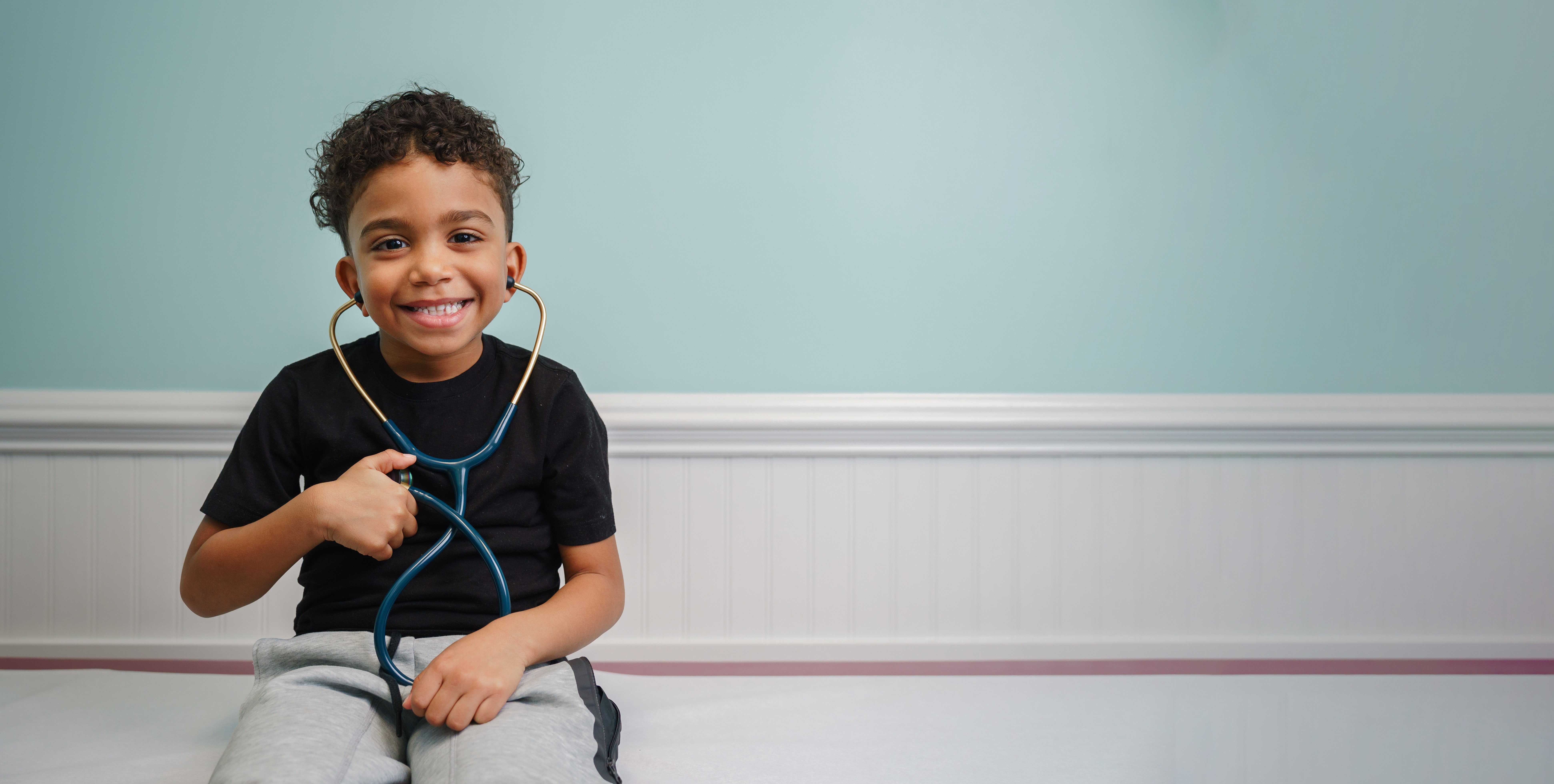 adolescent boy on exam table holding stethoscope