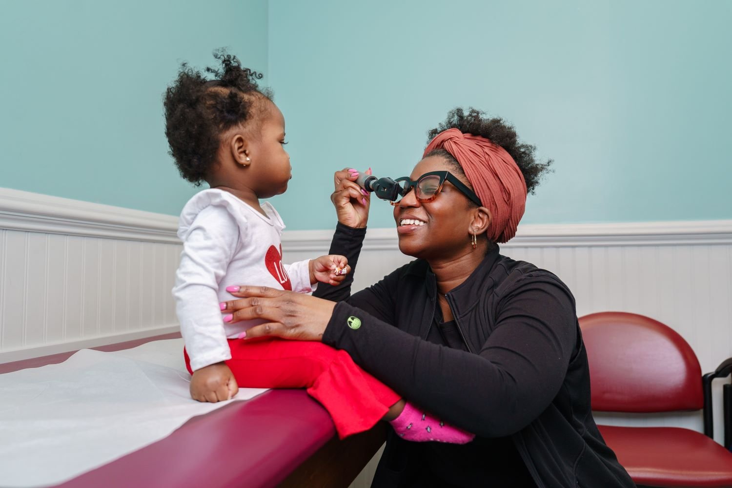 provider and toddler interacting on exam table