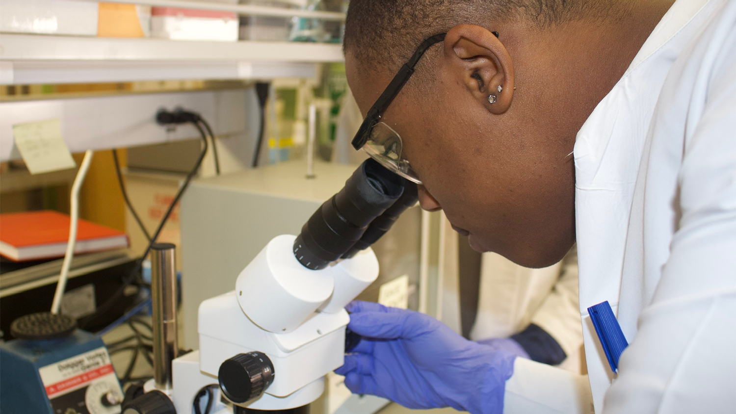 An intern analyzes microscopic specimens under the microscope, contributing to critical research study findings.