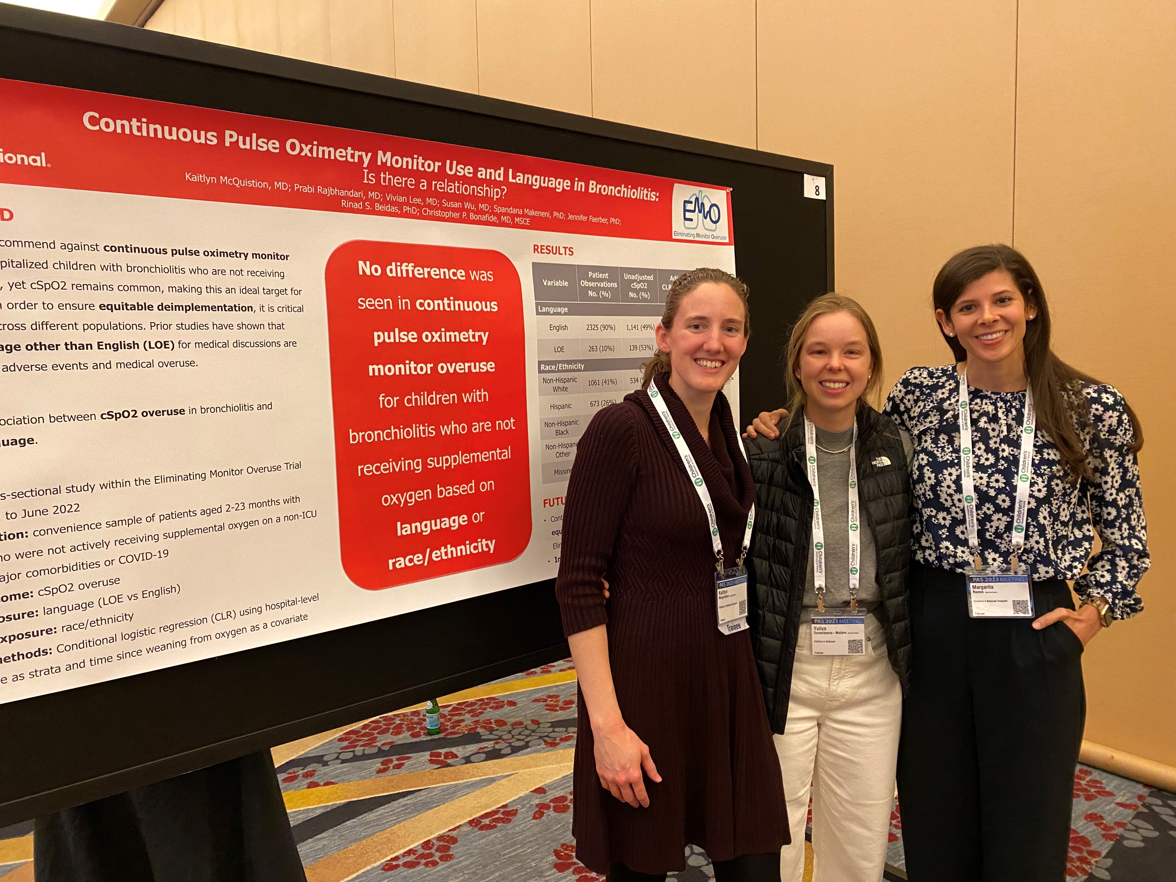 Three women smiling in front of their research poster