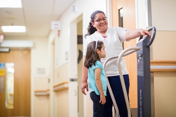 Little girl having her weight checked by a female nurse