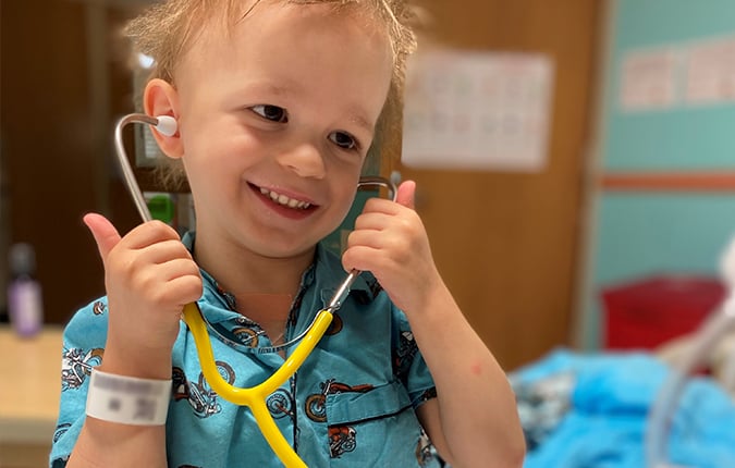 Patient Wes smiling while playing with a stethoscope