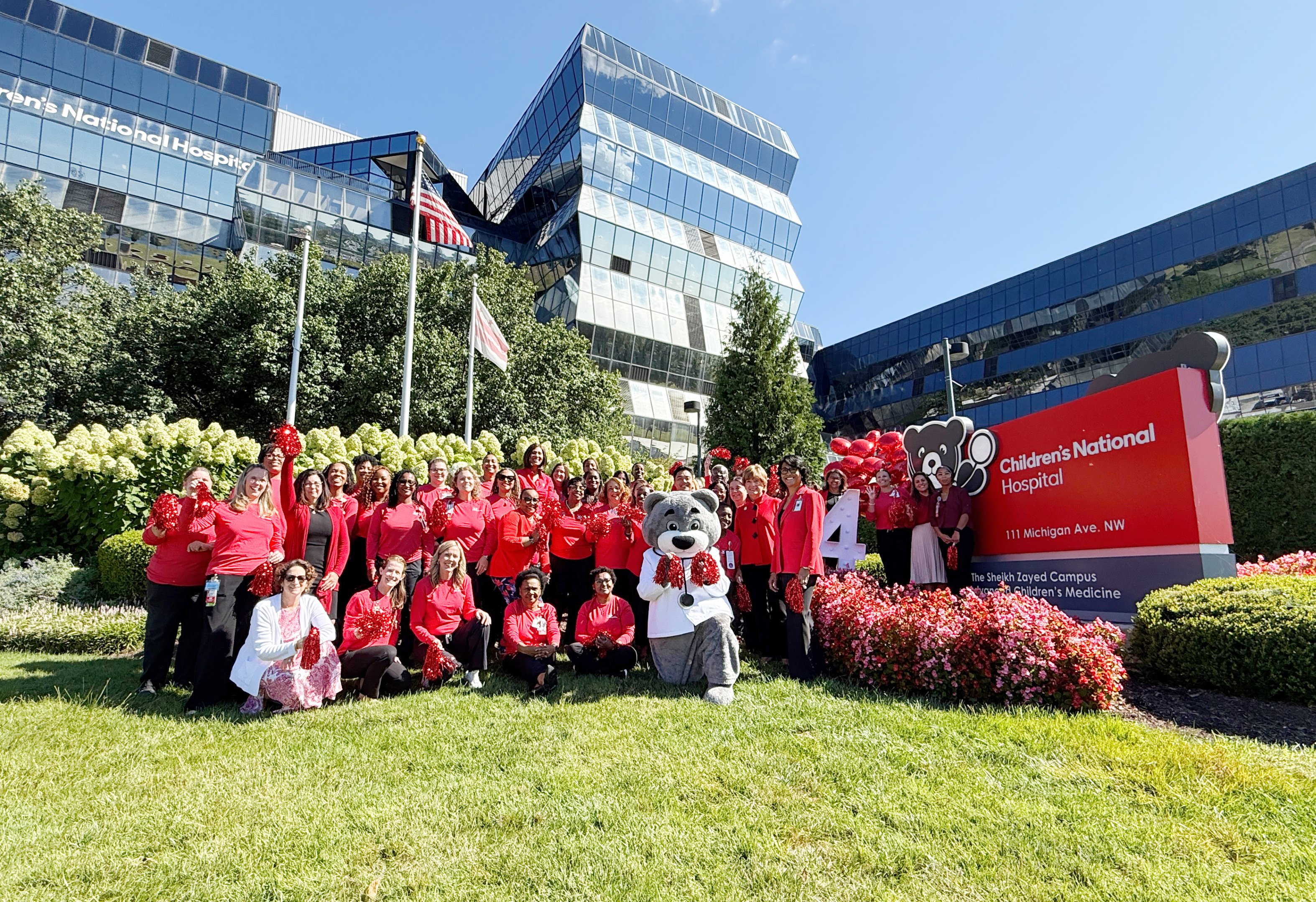Dr. Bear mascot surrounded by nurses and hospital leadership outside of Children's National Hospital.
