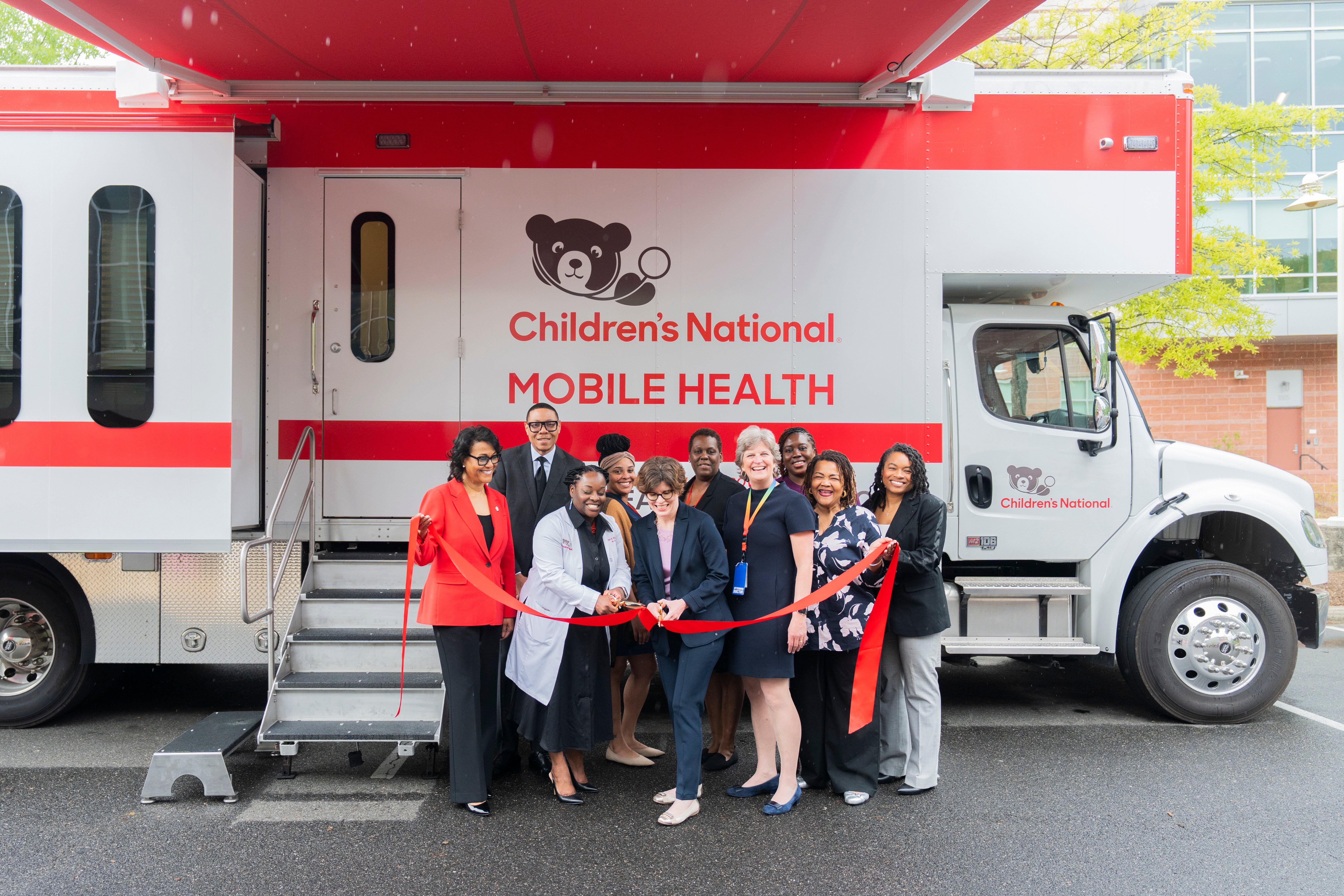 Leadership from Children's National Hospital and the D.C. government cut a ribbon in front of the Mobile Health Unit.