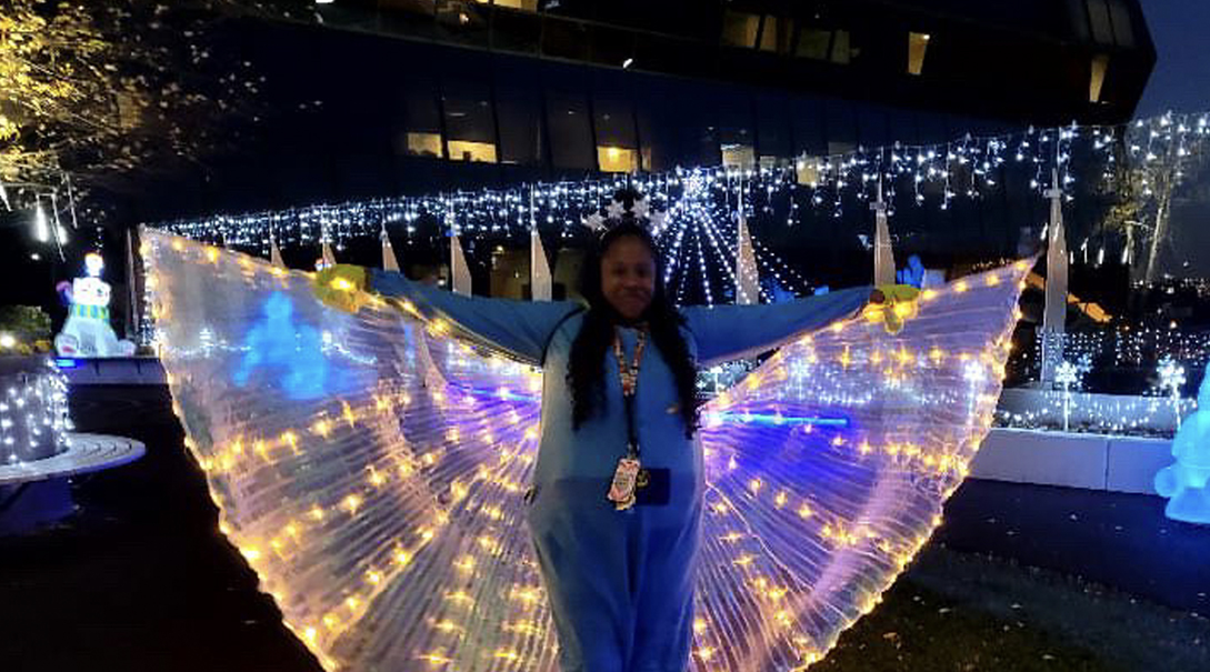 A hospital staff member dressed in illuminated wings at night in the Healing Garden