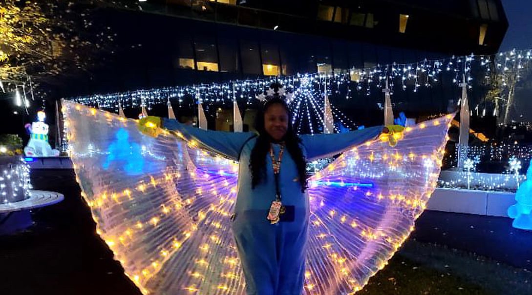 A hospital staff member dressed in illuminated wings at night in the Healing Garden
