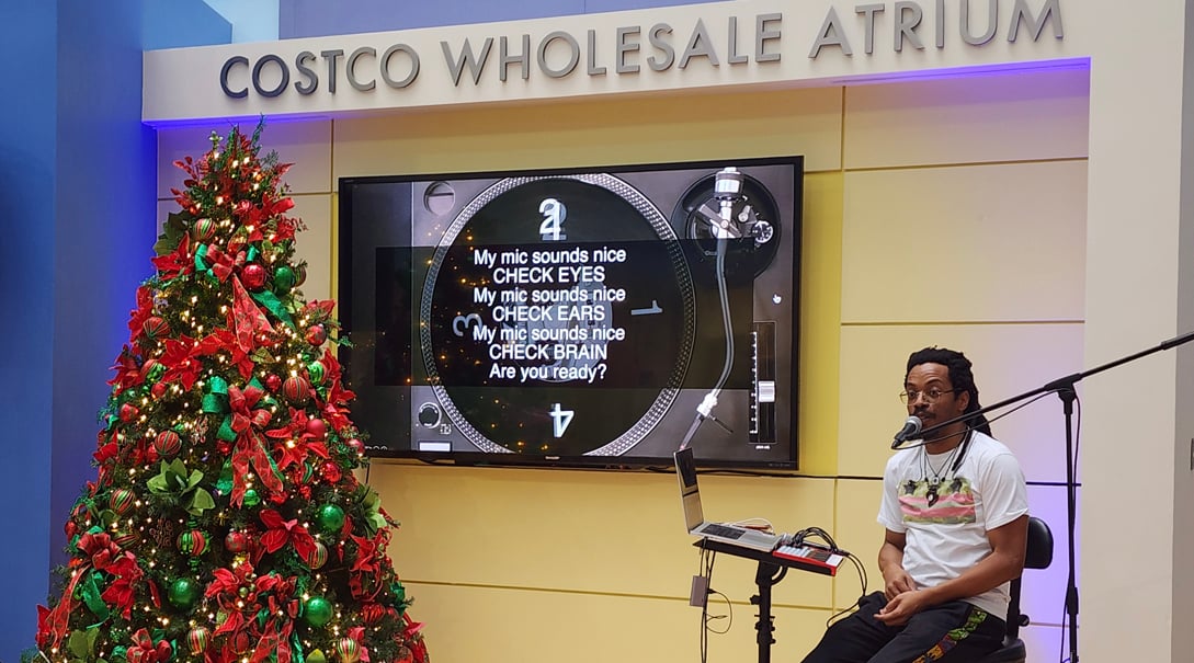 Musician performing in the Costco Wholesale Atrium near a decorated Christmas tree
