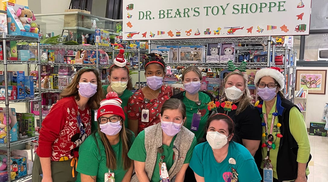 Several Hospital staff members posing next to shelves of toys in Dr. Bear's Toy Shoppe