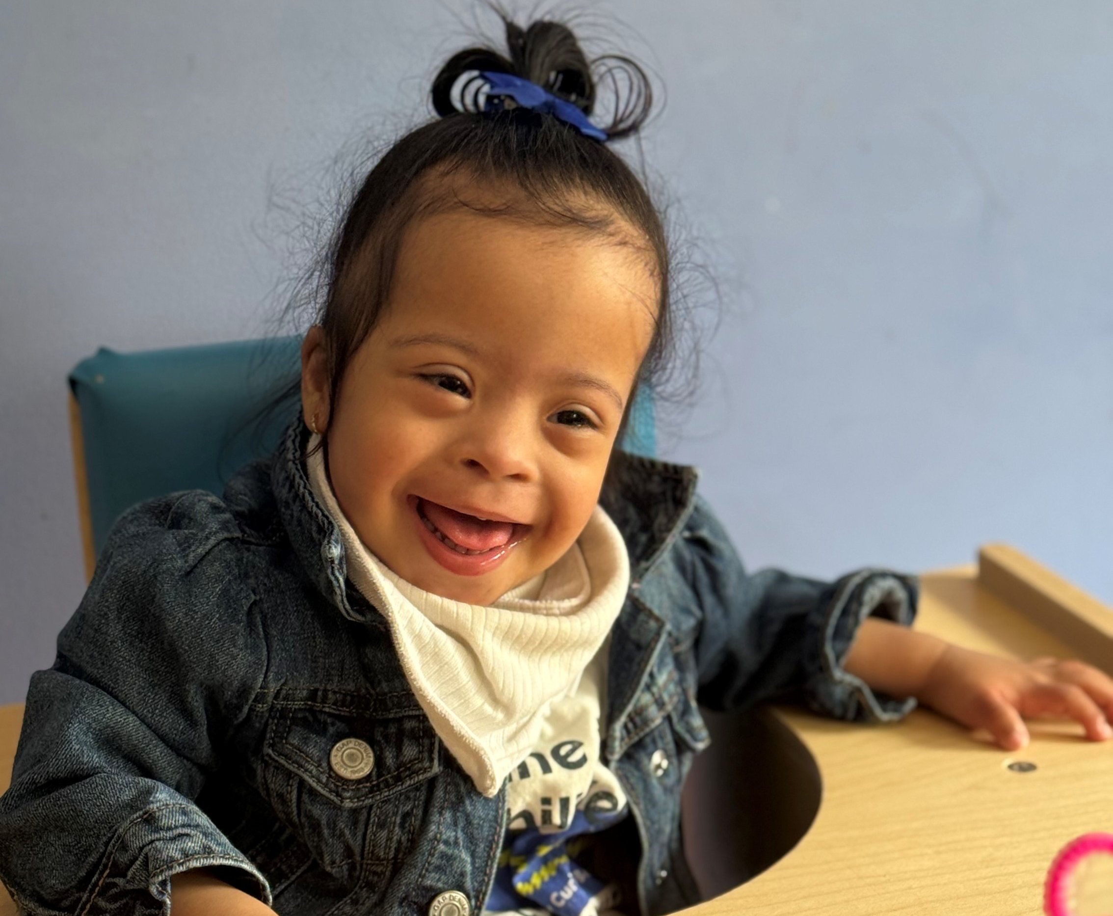 CNH patient, Raya, sitting in a chair and smiling.