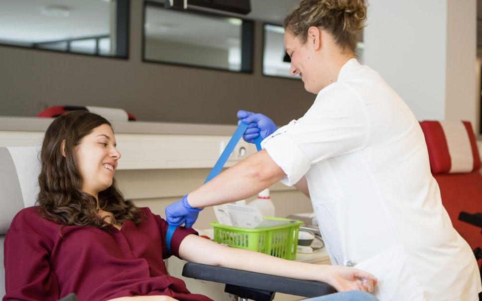 A woman sitting in a chair having her arm prepped for a blood donation.