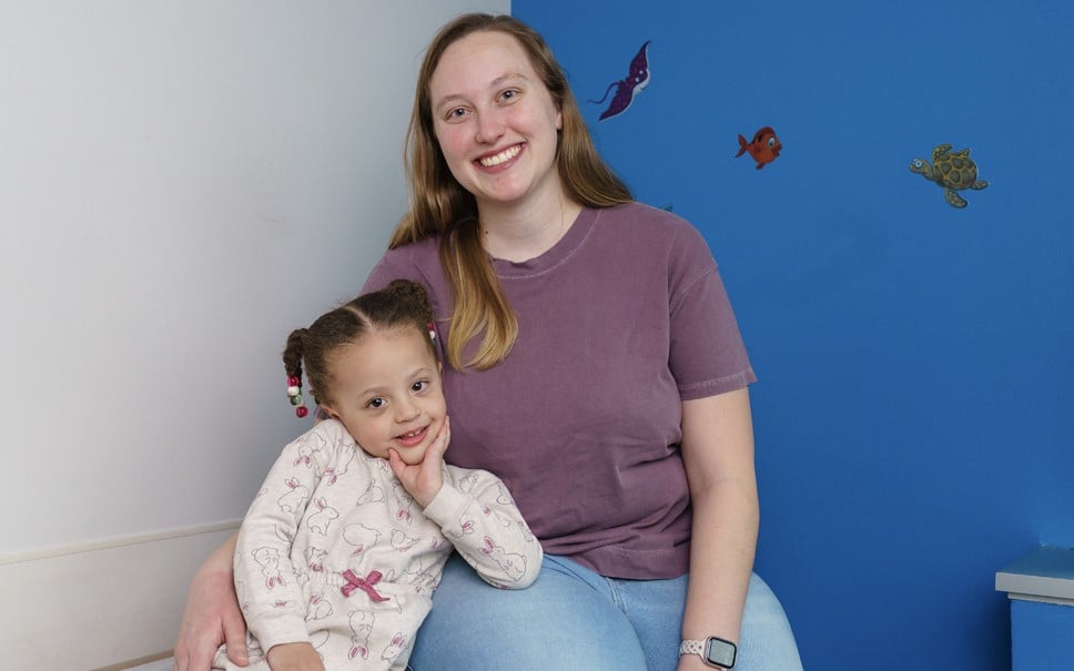 A woman and young female patient sitting together and smiling at the camera.