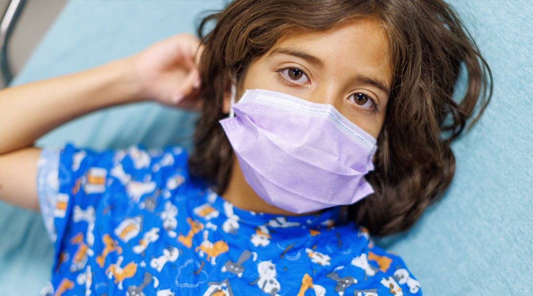 An elementary school aged child wearing a surgical mask.