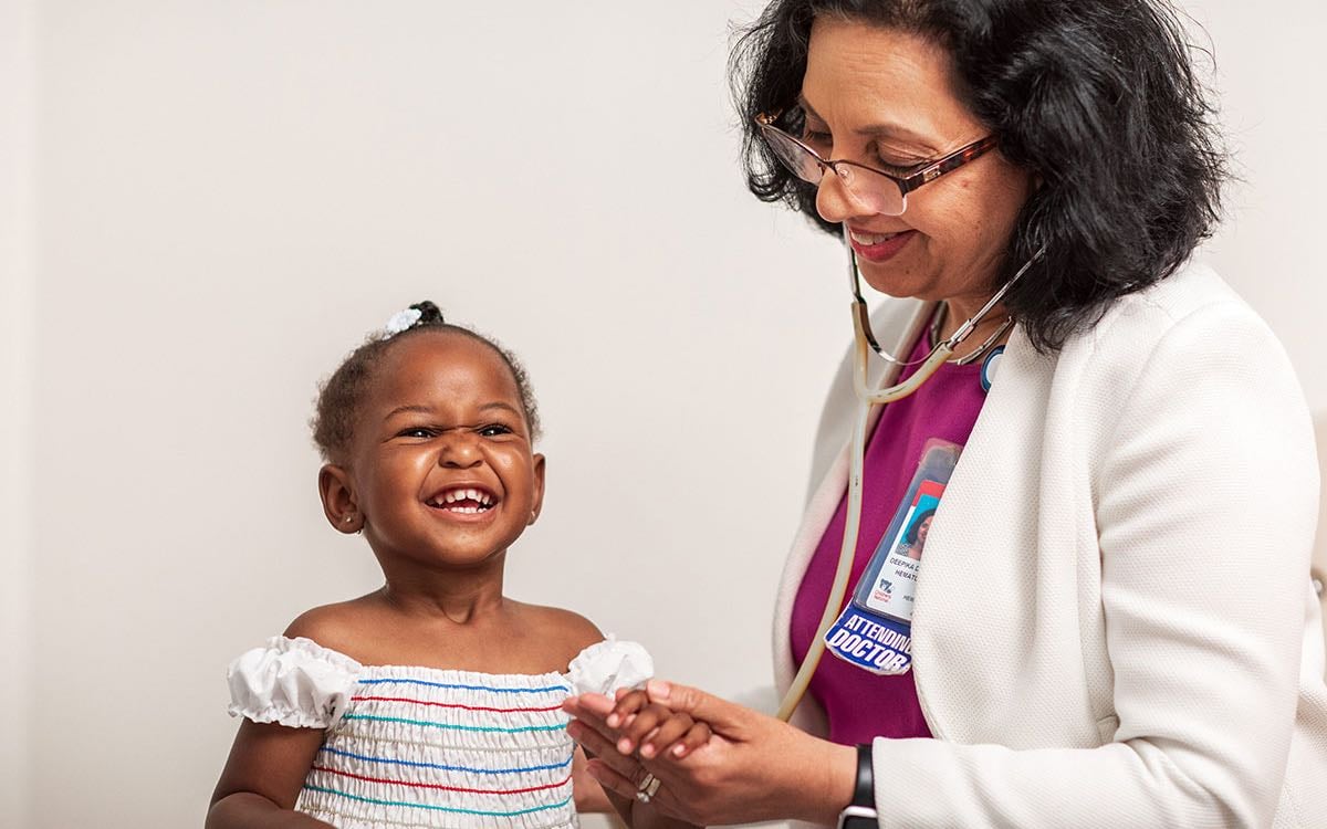 A Black female toddler aged patient gets examined by a female practitioner.