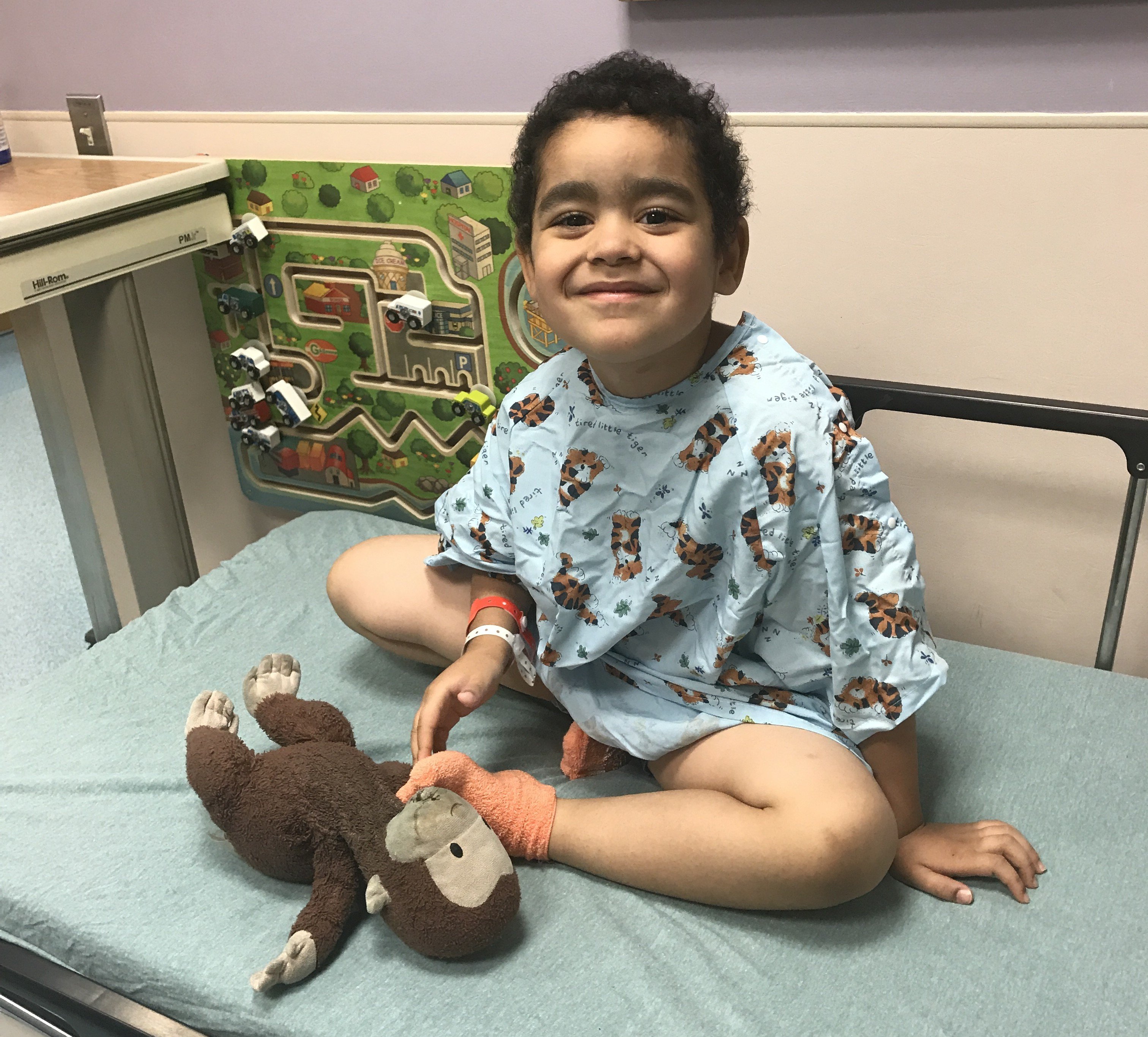 Ashley's son, Jonah, smiling while sitting on an examination table.