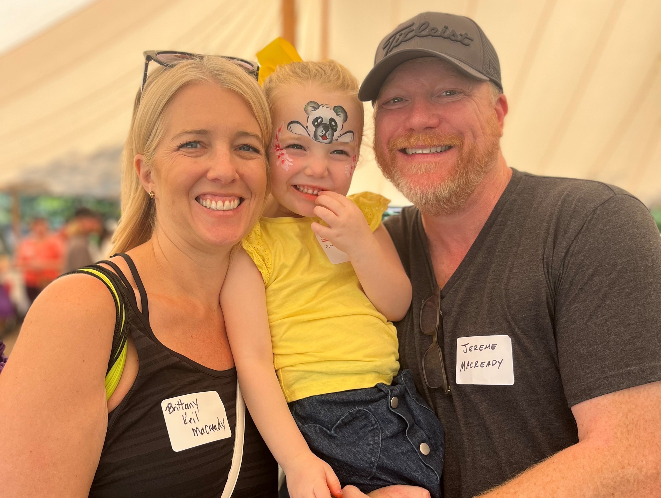 An older Fiona posing with her parents at a NICU reunion event.