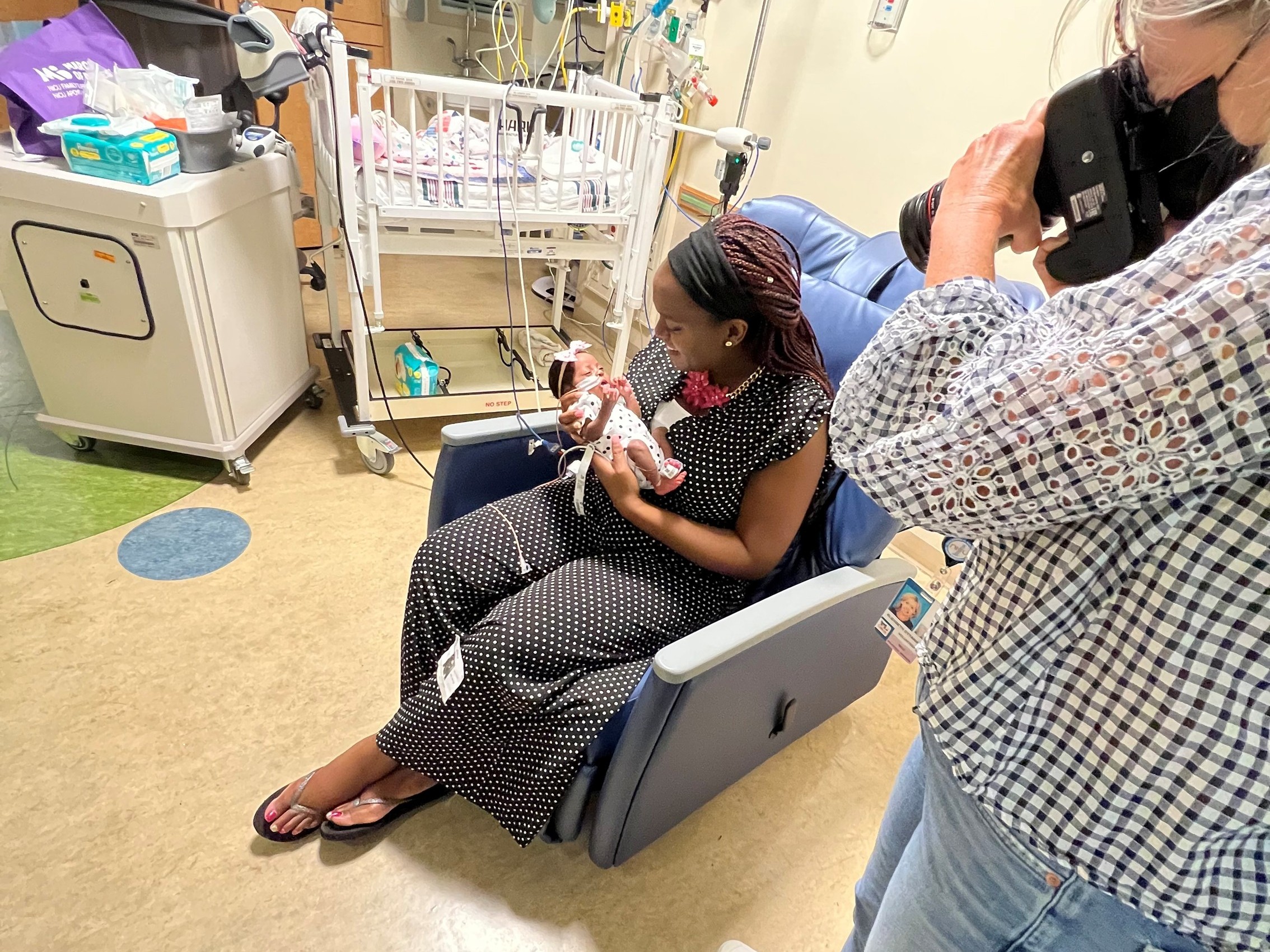 A volunteer takes photos with infant Mide and her mother.