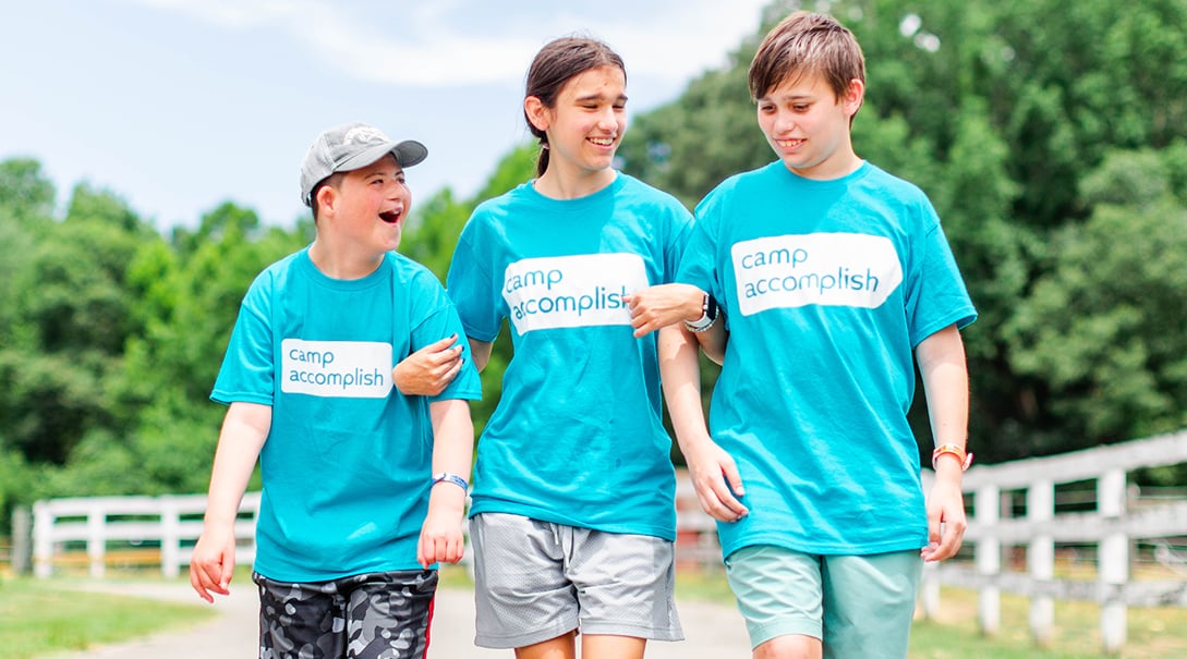 Three campers walk together while smiling and laughing.