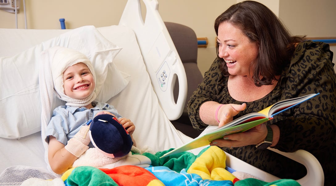 Allie Slocum reads to a patient in our Neuroscience unit