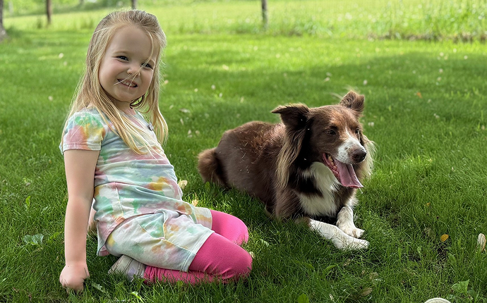 Fiona sitting in the grass with a dog.
